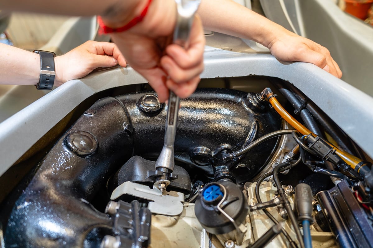 Marine mechanic servicing a boat engine with a wrench at a marina near Geelong
