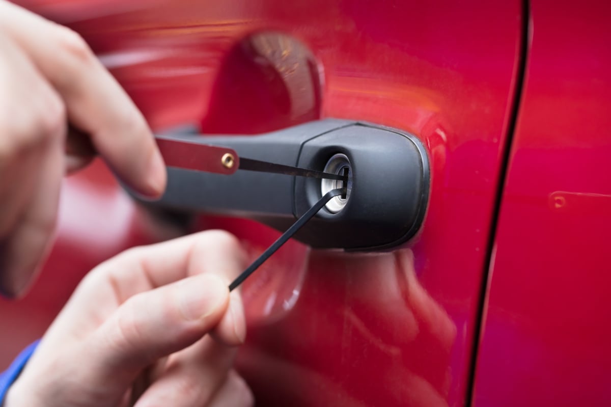 Automotive locksmith unlocking a red car door using a lockpicking tool on-site in Geelong